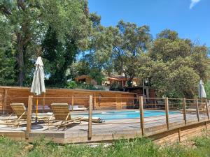a pool with chairs and umbrellas on a wooden deck at Brescou Lodges in Murviel +13 photos