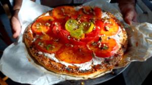 a pizza with tomatoes and peppers on top of it at Brescou Lodges in Murviel