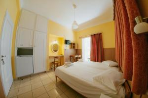 a bedroom with a white bed and a kitchen at Anna Christina in Kamena Vourla