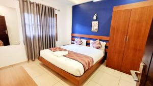 a bedroom with a bed with a blue wall at Hotel Wayanad Gate in Wayanad