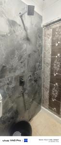 a shower in a bathroom with a stone wall at AB lodge in Coimbatore