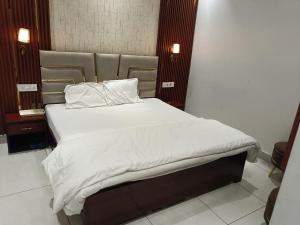 a bed with white sheets and pillows in a room at Hotel Deepjot in Karnal