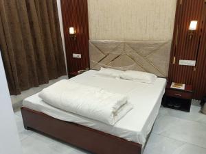 a bedroom with a bed with white sheets and pillows at Hotel Deepjot in Karnal +32 photos