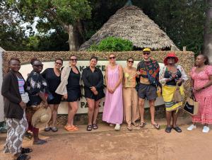 a group of people posing for a picture in front of a thatch roof at PASIFIC OCEAN TOUR's in Wasini Island