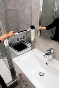a person standing in a bathroom with a sink at Miki Stays - 700m zum Ring in Vienna +35 photos