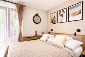 a bedroom with a bed and a clock on the wall at Baltic Sand - Apartamenty I Pokoje Władysławowo in Władysławowo