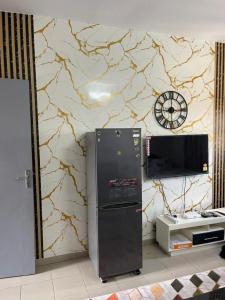 a refrigerator next to a wall with a clock at Studio Angre Mahou in Cocody
