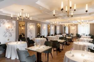 a restaurant with white tables and chairs and chandeliers at Hotel Villa Del Sogno in Gardone Riviera
