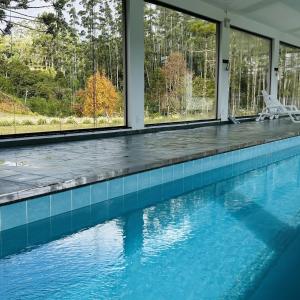 a swimming pool with blue tile and windows at Pousada Ritmos da Terra - Estadia de 6ª a Domingo in Angelina