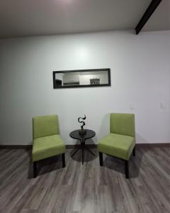 two green chairs and a table in a room at Apartamento Moderno Cosmopolitan Tower in San José
