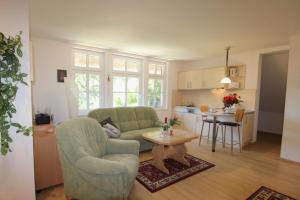 a living room with a couch and a table and a kitchen at Haus Koppelweg FW-Fisch in Ahrenshoop