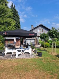 a patio with a black tent and white tables and chairs at Le chalet d Egide in Waimes