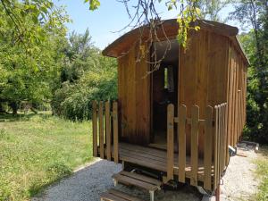 a wooden out house with a fence in a park at La Roulotte by Maison Maliga in Saint-Pierre-de-Curtille
