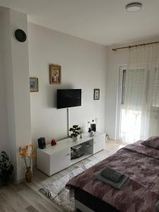 a white bedroom with a bed and a flat screen tv at Sumski Kutak in Valjevo