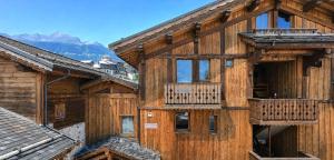 a wooden building with a balcony and mountains in the background at Le Tyrol in La Plagne Tarentaise