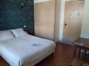 a bedroom with a bed and a table and a door at Auberge des Volcans in Saint-Chamant