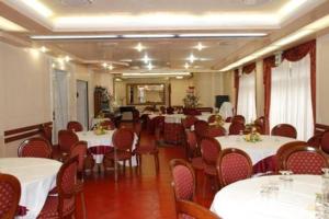 a dining room with white tables and red chairs at Hotel Burchiello in Mira