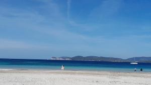 a group of people walking on the beach at Brezza marina in Alghero