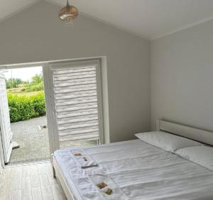 a white bedroom with a bed and a sliding glass door at Noclegi Pod Orłami in Lubaczów