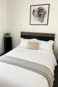 a bedroom with a large bed with white sheets at Stadium View Retreat at Olympic Park in Sydney