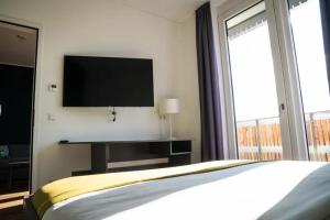 a bedroom with a bed and a tv on the wall at Das ELB Hotel & Restaurant in Magdeburg
