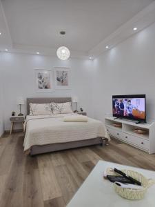 a white bedroom with a bed and a flat screen tv at Alfi apartments 1 in Belgrade