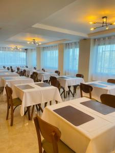 a room with white tables and chairs and windows at Le Bonne Ville Hotel in Campos do Jordão