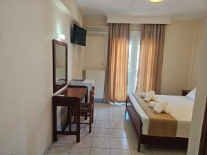 a bedroom with a bed and a desk and a mirror at Philippos Hotel in Paralia Katerinis