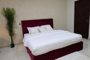 a bedroom with a large bed with white sheets and a palm tree at Maya Lodge in Accra