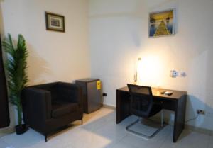 a living room with a chair and a desk and a television at Maya Lodge in Accra +12 photos