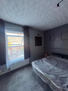 an empty bedroom with a bed and a window at Ca stays in Heywood