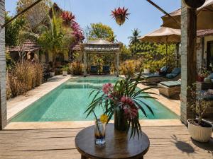 a swimming pool with a table with flowers on it at Meno Dream Resort in Gili Meno