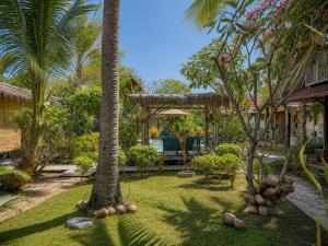 a yard with a palm tree and a house at Meno Dream Resort in Gili Meno
