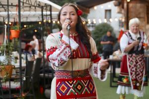 two women in traditional clothing singing into a microphone at ODAYA Social Hotel Bansko in Bansko