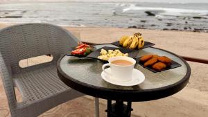 a table with a plate of food and a cup of coffee at Roushan Resort Salalah Mirbat in Mirbāţ
