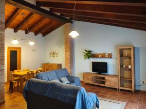 a living room with a blue couch and a television at Casa Les Donfelises in Peñarroya de Tastavins