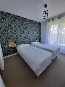 two beds in a bedroom with a floral wallpaper at Louis Hotel in Perros-Guirec