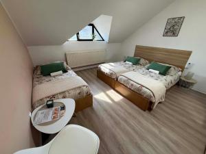 a bedroom with two beds and a table and a window at Rooms Osmica- Videm pri Ptuju in Videm pri Ptuju