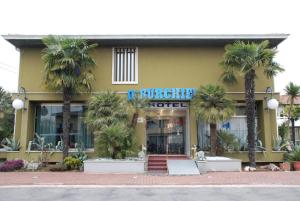 a yellow building with palm trees in front of it at Hotel Burchiello in Mira +22 photos