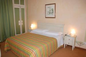 a bedroom with a bed with a striped blanket and two lamps at Hotel Burchiello in Mira