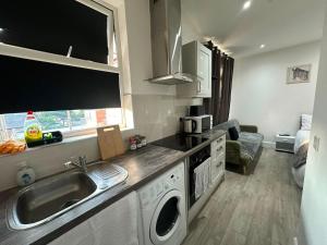 a kitchen with a sink and a washing machine at Wimbledon chase self- catering studio in Raynes Park