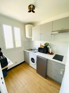 a kitchen with white cabinets and a washer and dryer at Studio centre ville in Concarneau