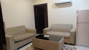 a living room with a couch and a chair and a refrigerator at ستارلت للشقق المخدومة in Buraydah