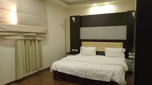 a bedroom with a large bed with white sheets and pillows at ستارلت للشقق المخدومة in Buraydah