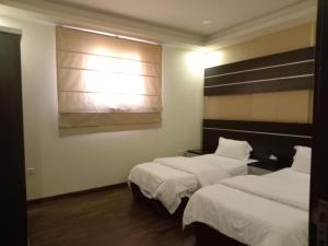 a hotel room with two beds and a window at ستارلت للشقق المخدومة in Buraydah