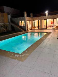 a large swimming pool with blue water at night at Villa TaouBa in Ghazoua