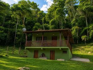 a green house with a balcony on top of it at Chalé Céu de Minas in Visconde De Maua