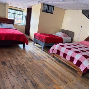 a room with two beds with red covers and wooden floors at Hostal Mediodía MATRIZ in Quito