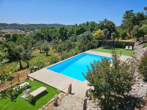 an image of a swimming pool in a garden at Quinta do Penedo- Refúgio de Charme e Natureza in Ferreira do Zêzere