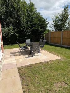 a patio with a table and chairs on the grass at 25 Birch House in Oswestry
